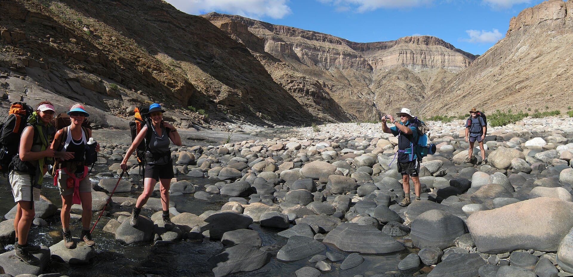 Hikers crossing the rocky Fish River Canyon floor in Namibia