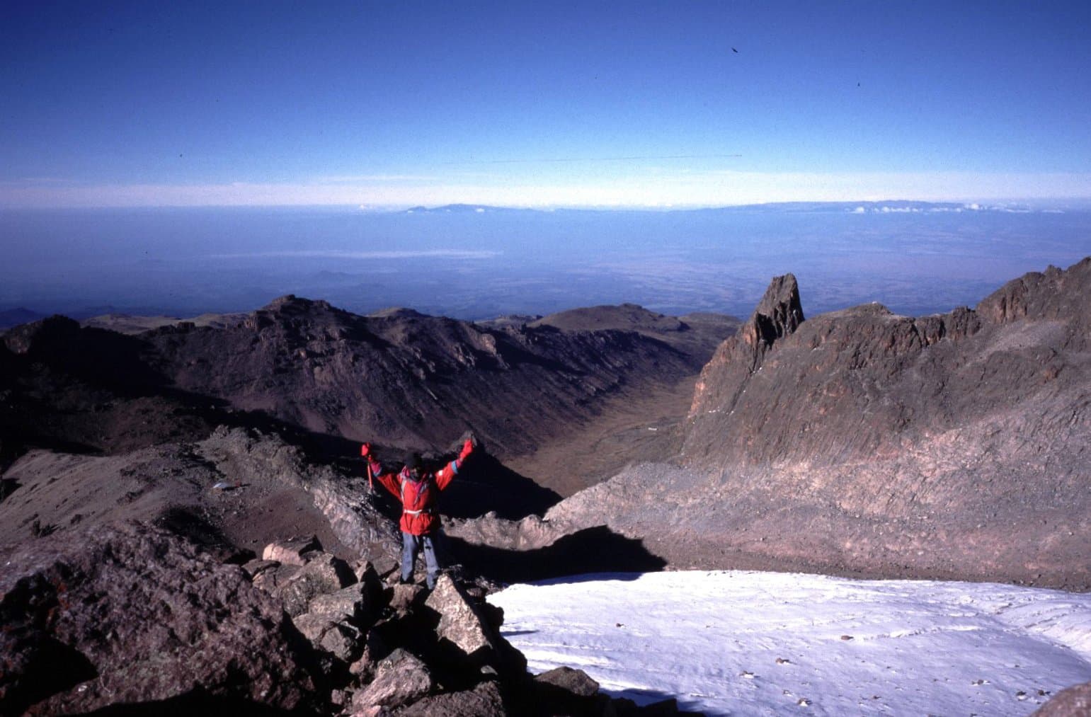 A trekker above the glacier and rocky high peaks of Mount Kenya